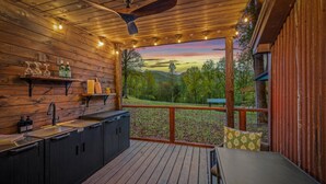 A wooden deck with a built-in kitchen area, including a sink and cabinets, overlooking a scenic landscape. - The Tree Spa, Tiny Cabin w/ Hot Tub in the trees (Hayesville)