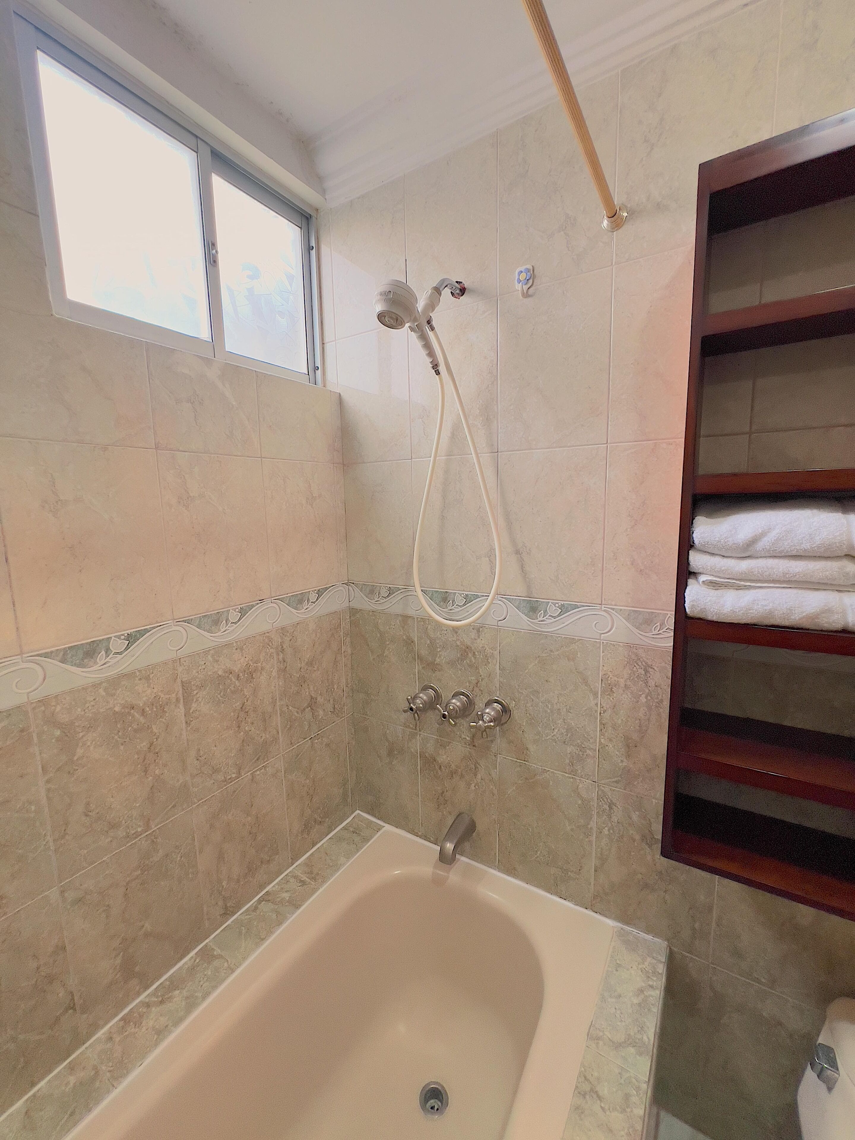 A bathroom with a bathtub, a showerhead, and a towel rack.