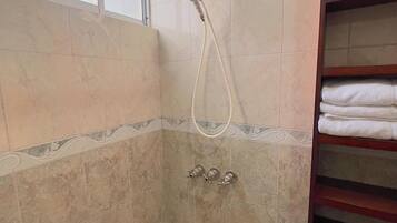 A bathroom with a bathtub, a showerhead, and a towel rack.
