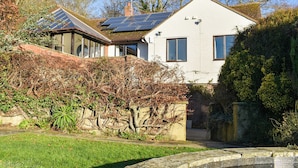 A house with solar panels on the roof, a garden with a pond, and a brick wall. - Pines Cottage - UK42110 (St. Margaret&rsquo;s Bay)