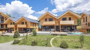 A row of wooden cabins with large windows, a swimming pool, and a grassy area. - Appealing Apartment With Pool (Sankt Georgen am Kreischberg)