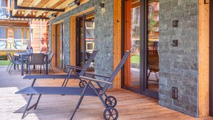 A wooden deck with outdoor furniture and stone walls. - Appealing Apartment With Pool (Sankt Georgen am Kreischberg)