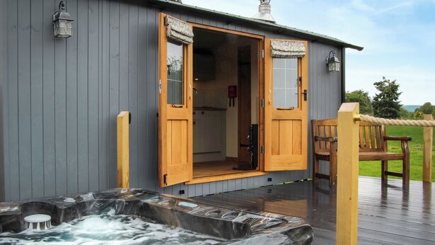 Een wellnessruimte met een bubbelbad en een houten terras.