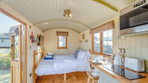 Een gezellige kamer met een bed, een raam, een kitchenette en uitzicht op de omgeving.