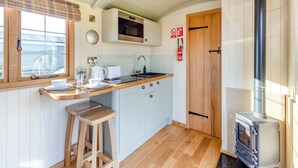 Een moderne keuken met een houten aanrecht, een ingebouwde magnetron, een fornuis en een raam met jaloezieën.