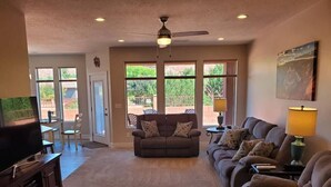 A living room with a sofa set, a television, and a ceiling fan.