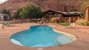 A swimming pool with a wooden deck, lounge chairs, and a mountain backdrop.