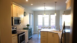 A modern kitchen with stainless steel appliances, a dining area with a large window, and a small island with seating.
