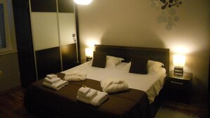 Una habitación de hotel con una cama, dos mesitas de noche, un armario y un adorno en la pared.