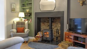 A cozy living room with a fireplace, a television, and a comfortable armchair.