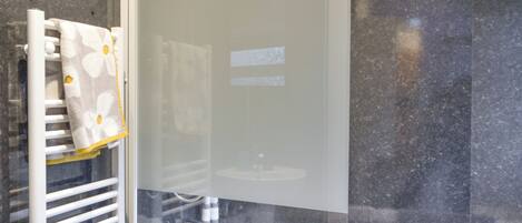 A bathroom with a glass-enclosed shower, a white sink, and a towel rack with a patterned towel.