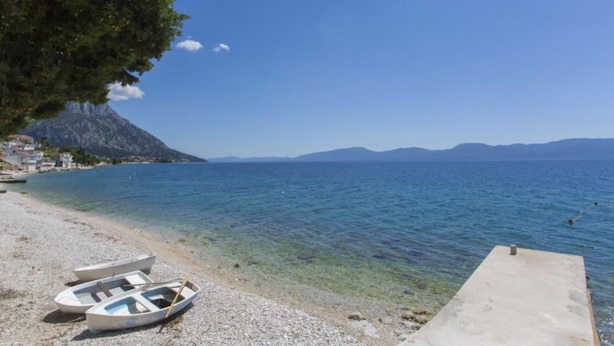 A pebble beach with boats and a concrete platform. - Triple Room with Private Balcony (Brist)