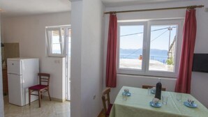 Ein Essbereich mit Tisch für zwei Personen, einem Kühlschrank und einem Fenster mit Meerblick.