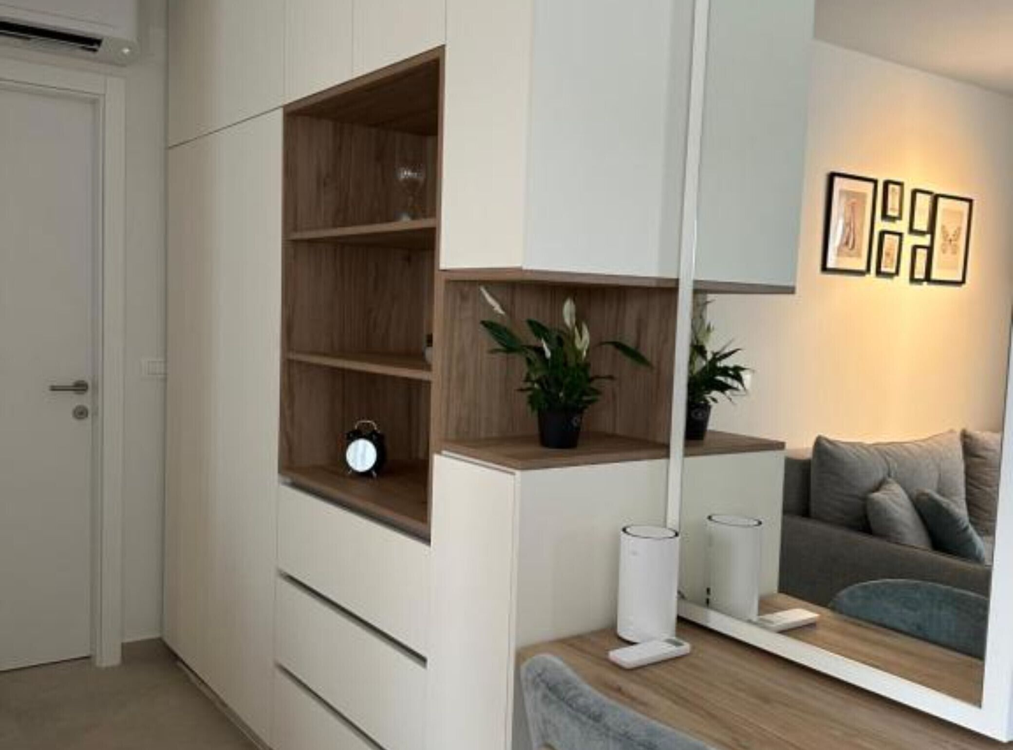 En moderne stue med indbyggede reoler, en sofa, et sofabord og et spejl der reflekterer rummet.