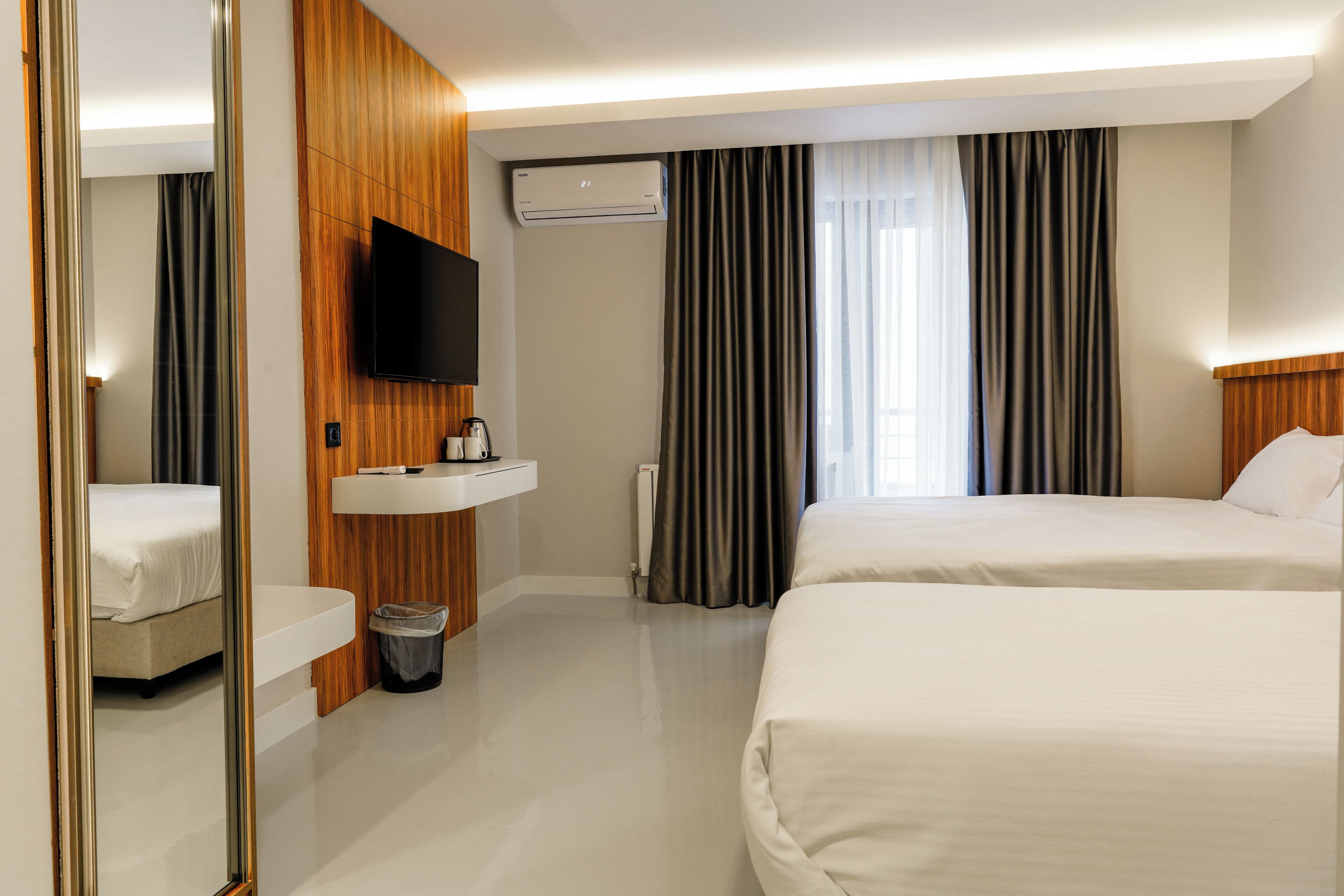 Une chambre d’hôtel avec deux lits, une télévision, un lavabo et un miroir.