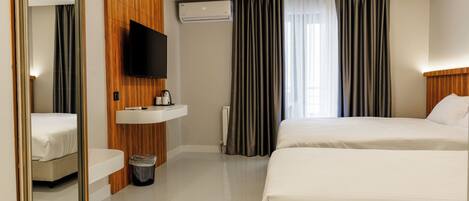 Une chambre d’hôtel avec deux lits, une télévision, un lavabo et un miroir.