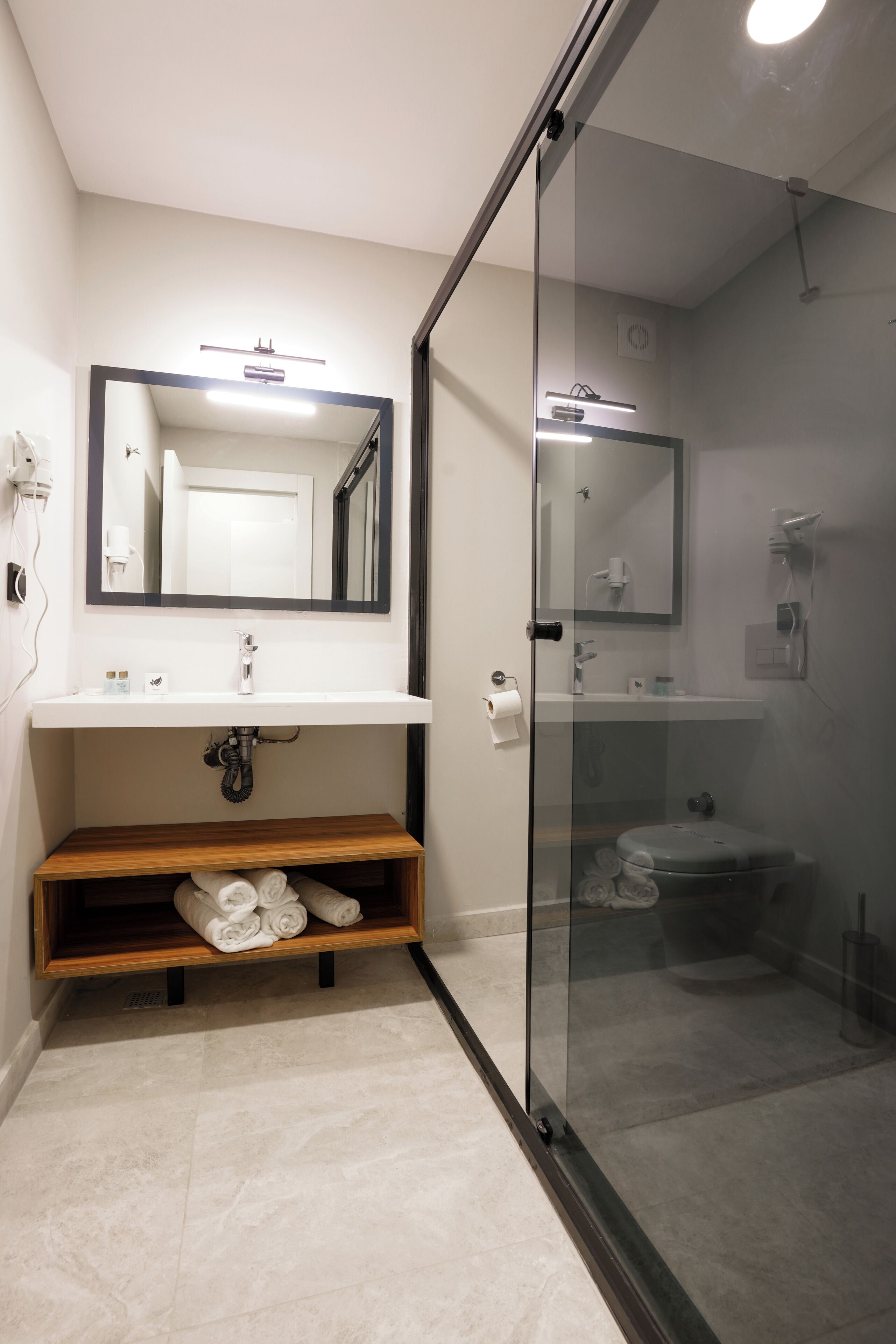 A modern bathroom with a glass shower enclosure, a wooden vanity, and a large mirror above the sink.