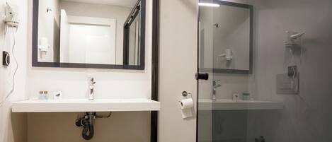 A modern bathroom with a glass shower enclosure, a wooden vanity, and a large mirror above the sink.