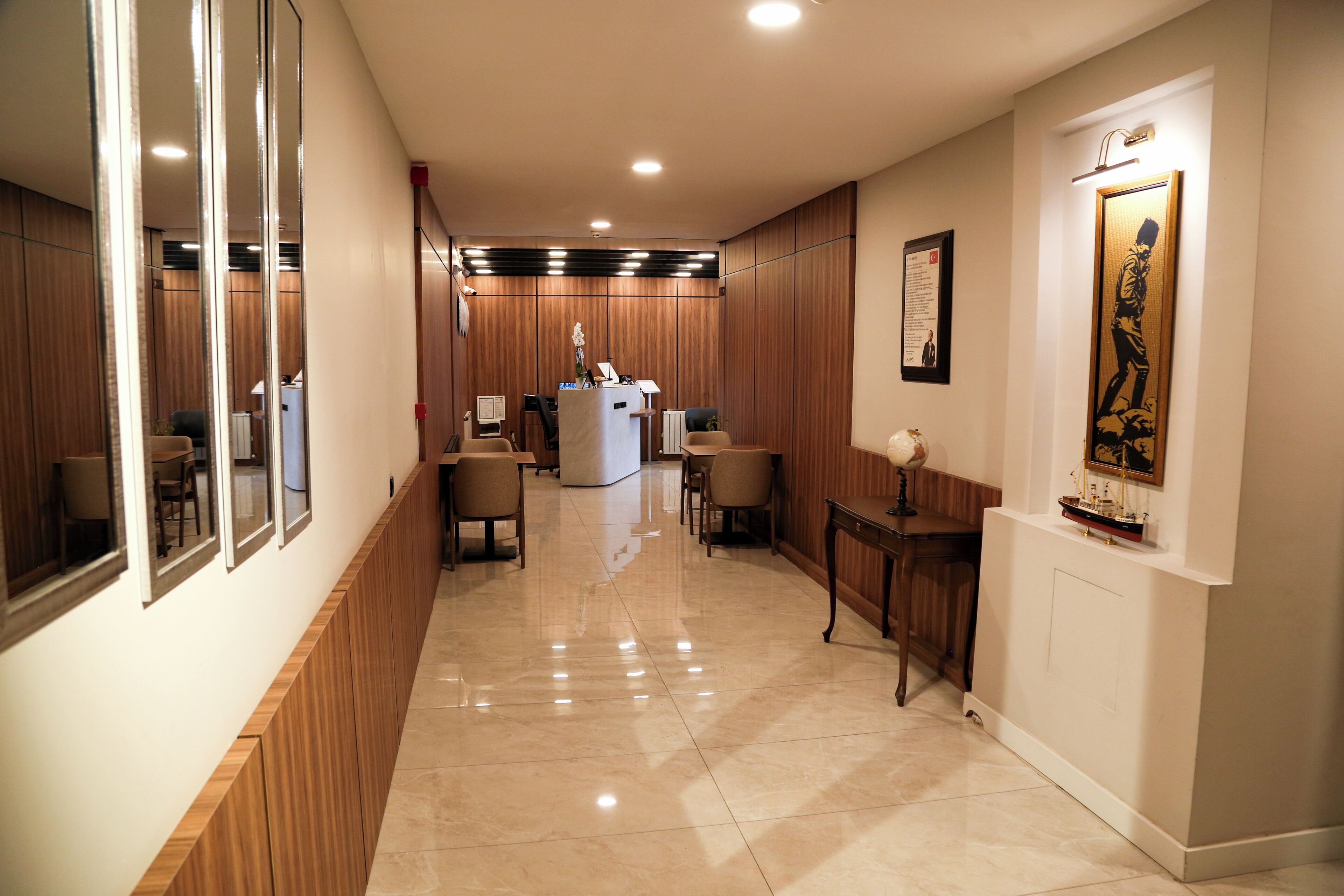 A hotel corridor with wooden paneling, a reception desk, and several seating areas.