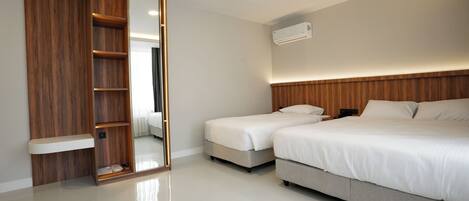 A modern bedroom with a wooden wardrobe, a large mirror, a bed with white bedding, and a ceiling-mounted air conditioning unit.