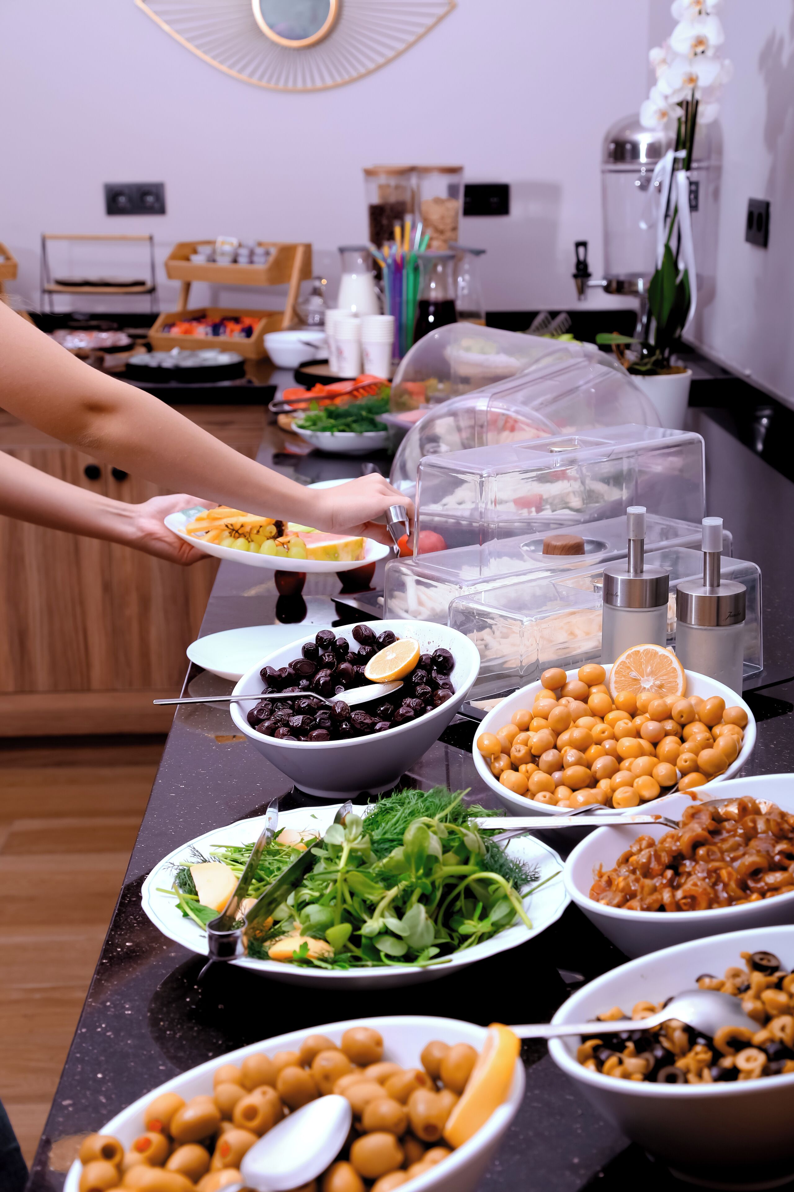 Una mesa de buffet con diferentes alimentos y una persona sirviéndose.