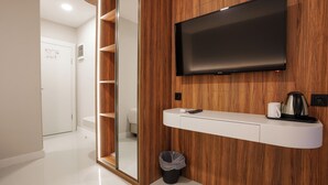 Ein modernes Badezimmer mit einem Holzbadezimmerwaschtisch, einem an der Wand montierten Fernseher und einem Spiegel.