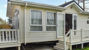 A mobile home with two windows, a front door, and a small porch with steps. - 2 bedroom accommodation in Towyn (Towyn)