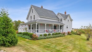 A two-story house with a covered porch and a chimney. - Maine Getaway with Stunning Water Views-Kayak, SUP, & More! (Kennebunk)