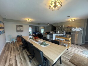 A modern kitchen with a dining area, wooden flooring, and contemporary lighting fixtures.