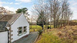 A white house with a steep roof and a gravel driveway.