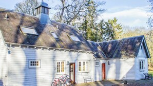 A white wooden house with a sloped roof, a chimney, and a small porch with a bench. - 3 bedroom accommodation in Blairgowrie (Blairgowrie)