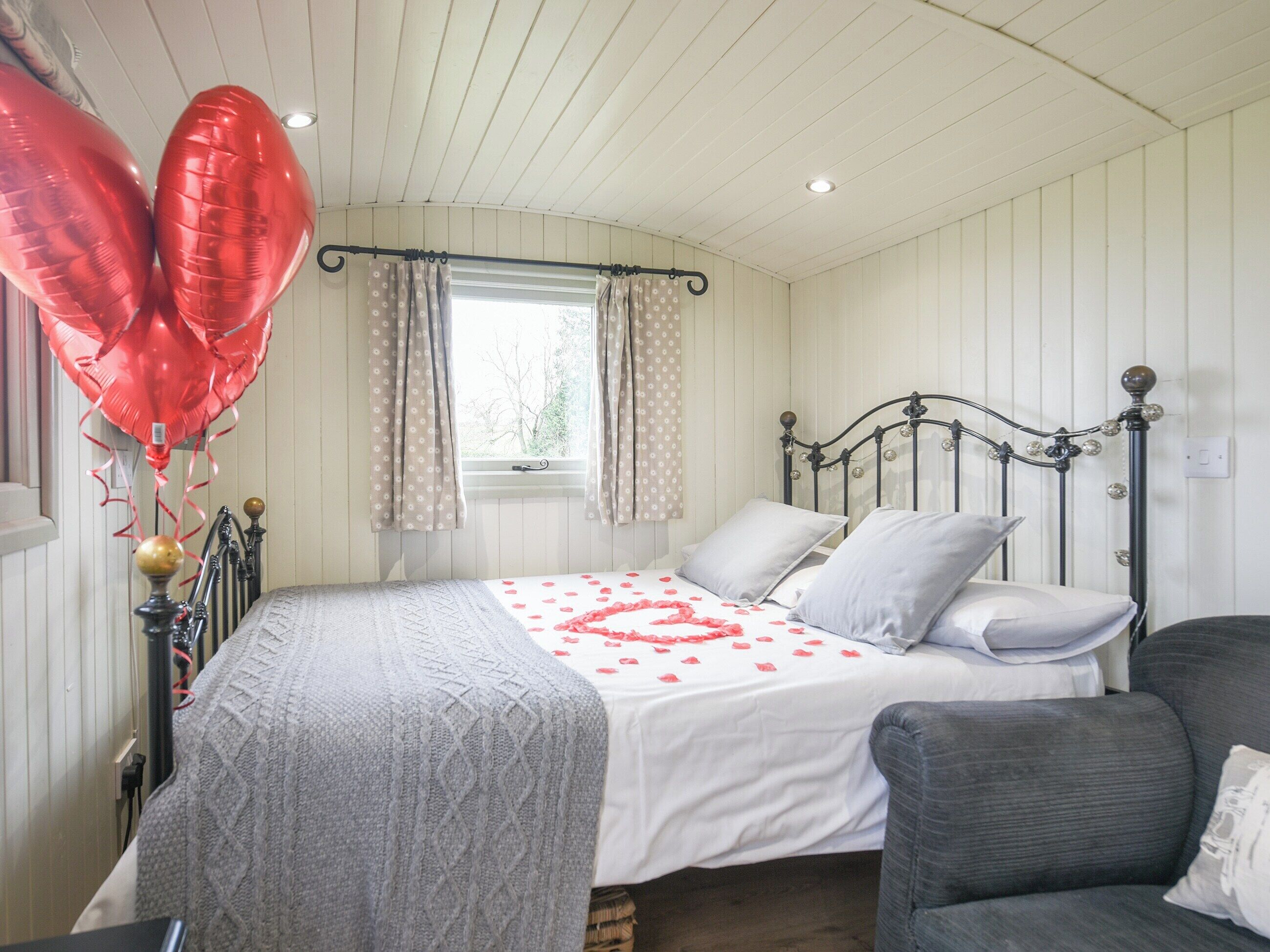 Een slaapkamer met een bed, een raam met gordijnen, een nachtkastje en een stoel.