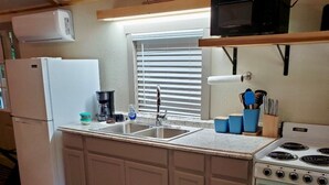A compact kitchen with a refrigerator, stove, microwave, and a sink. - Tunnel Mountain Getaways- Cozy Retreat with Scenic Views! (Elkins)