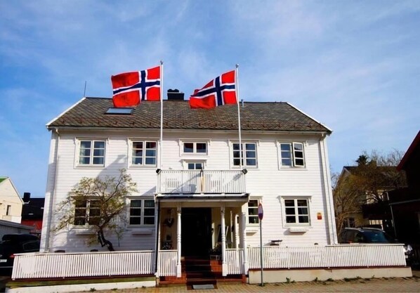 A white two-story building with a balcony and a porch.
