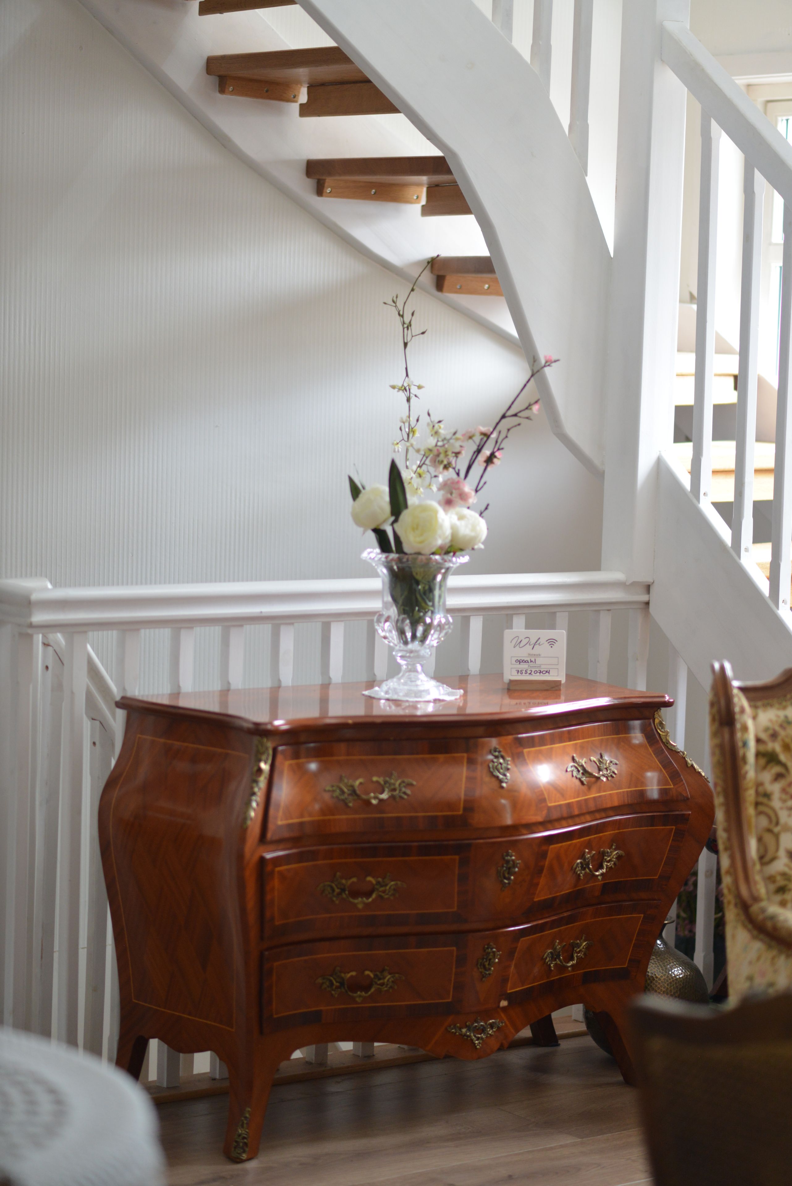 A wooden dresser with drawers and a vase of flowers on top.