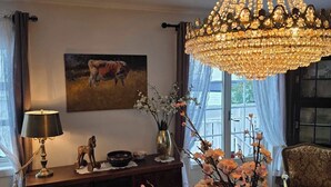 Un coin repas agrémenté d’un lustre, d’un tableau représentant un taureau, d’un bureau avec une lampe et d’un vase rempli de fleurs.