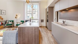 Una cocina moderna con una isla central, electrodomésticos integrados e iluminación colgante.