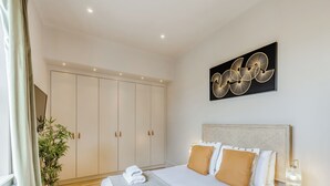 Habitación de hotel con una cama, una mesita de noche, una lámpara, una planta en maceta y un armario.