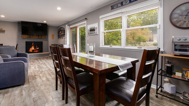 A dining area with a fireplace, a large window, and a kitchen area with a microwave. - Golden Shamrock<>3BR Home 3min to ND (South Bend)