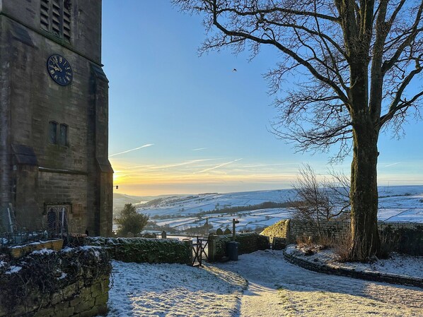 A snow-covered landscape with a stone building featuring a clock.