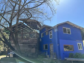 A two-story building with a blue exterior, a covered porch, and a stone wall.