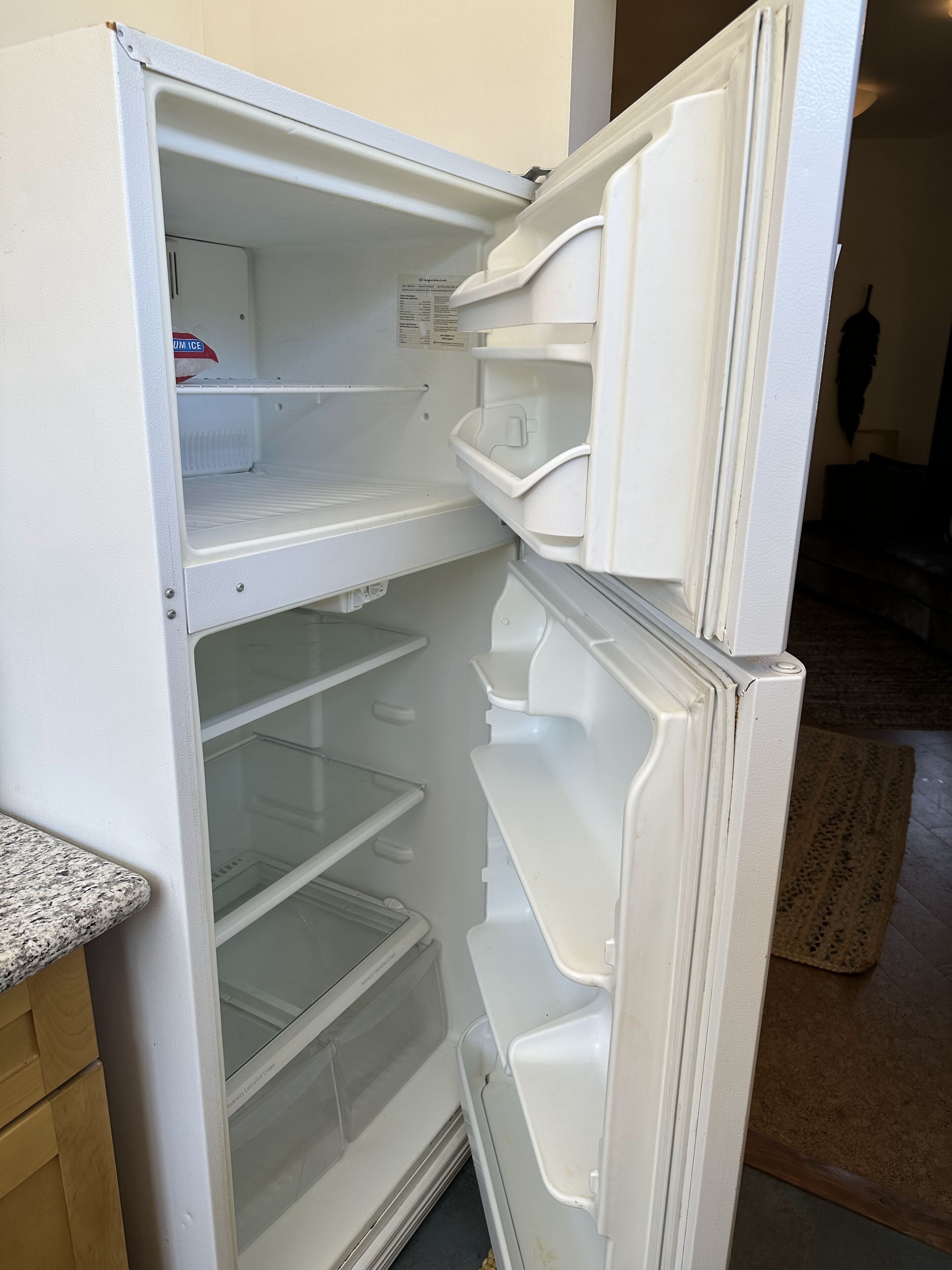 Un refrigerador abierto con varias estantes y un compartimento congelador.