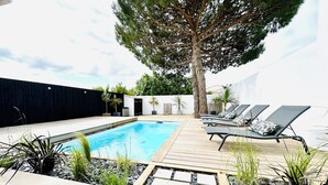 A swimming pool with a wooden deck, lounge chairs, and potted plants. - Beautiful villa with private pool - heart of the village (La Flotte)
