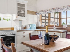 A kitchen with a wooden table, a bottle of champagne, and two wine glasses.