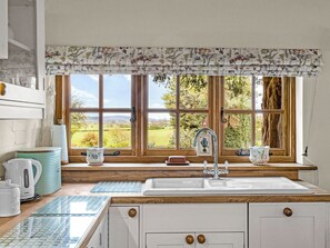 A kitchen with a large window, wooden cabinets, a sink, and various kitchen items. - 1 bedroom accommodation in Kynaston (Kynaston)