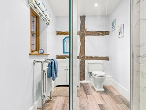 A bathroom with a glass shower enclosure, a white toilet, and a wooden beam accent. - 1 bedroom accommodation in Kynaston (Kynaston)