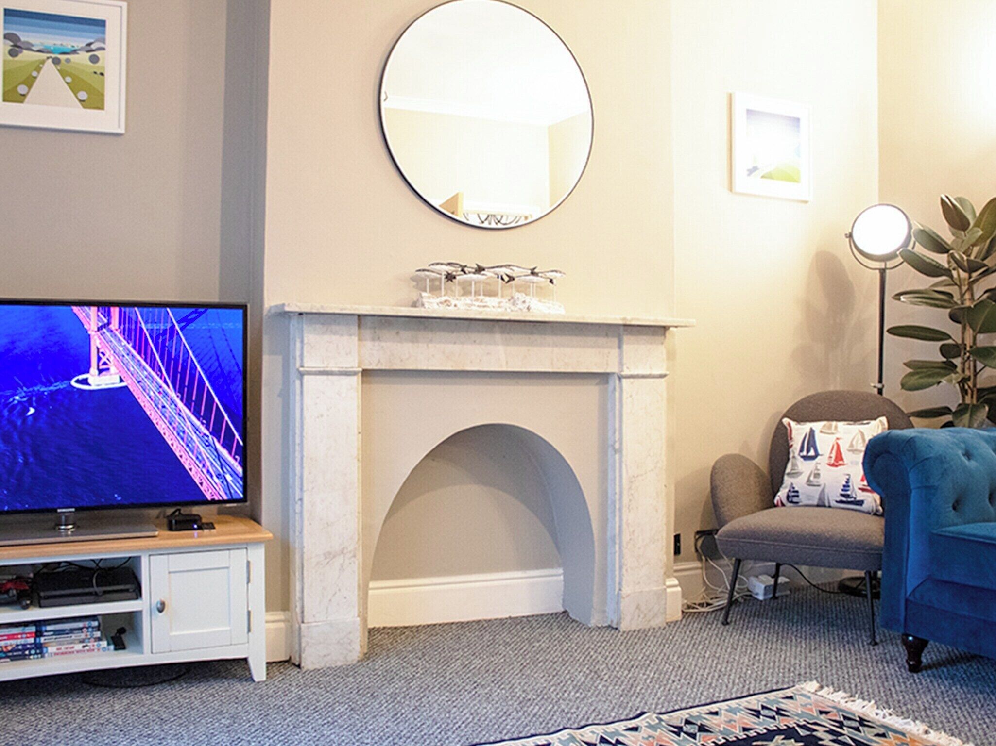 A living room with a television, a fireplace, a mirror, and a blue armchair.