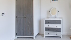 A room with a wardrobe, a dresser with drawers, a mirror, and a framed picture on the wall. - Coastal Soul - UK43464 (Lake, near Sandown)
