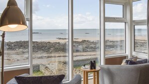 Ein Zimmer mit großen Fenstern und Meerblick, einer Lampe und zwei Sofas.