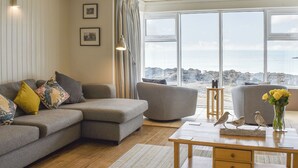 Ein Wohnzimmer mit einer Couch, einem Sessel und einem Holztisch mit Dekoration.